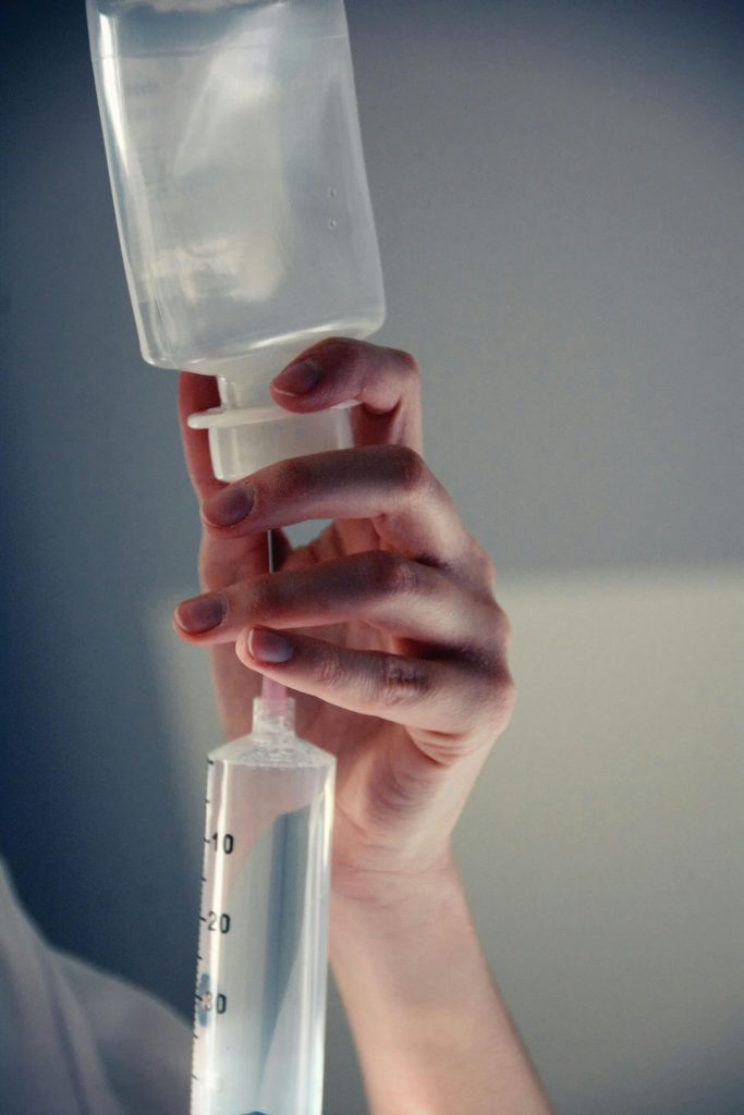 Detailed close-up of a hand holding an IV fluid bag in a medical setting.