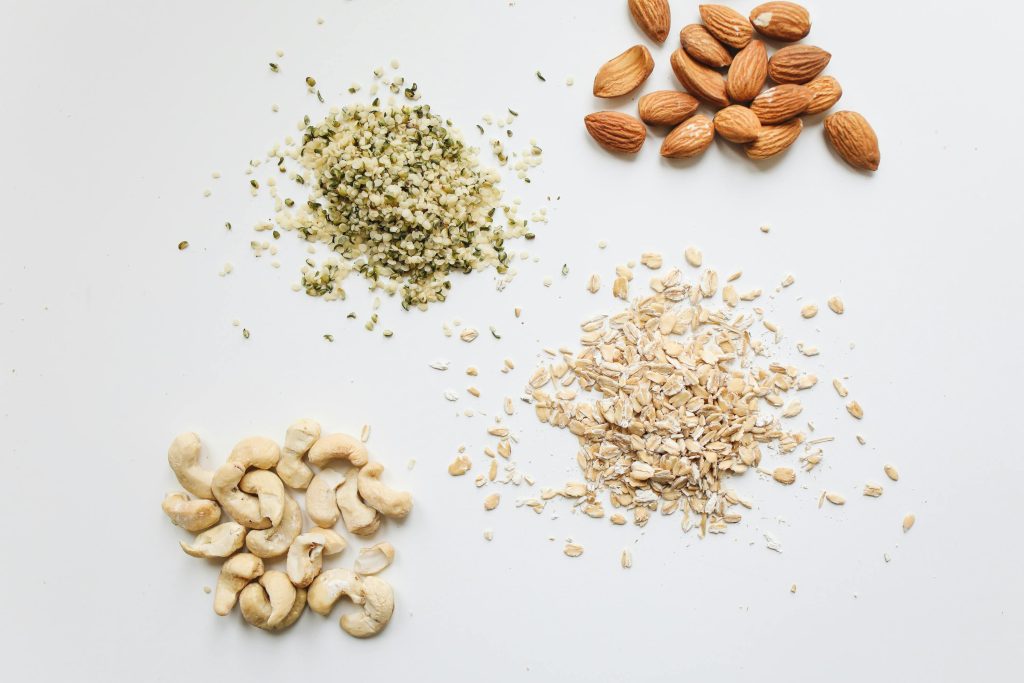 Top view of almonds, cashews, oats, and hemp seeds on white background.