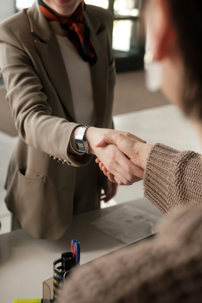 Two professionals shaking hands in an office, signifying a successful business agreement.
